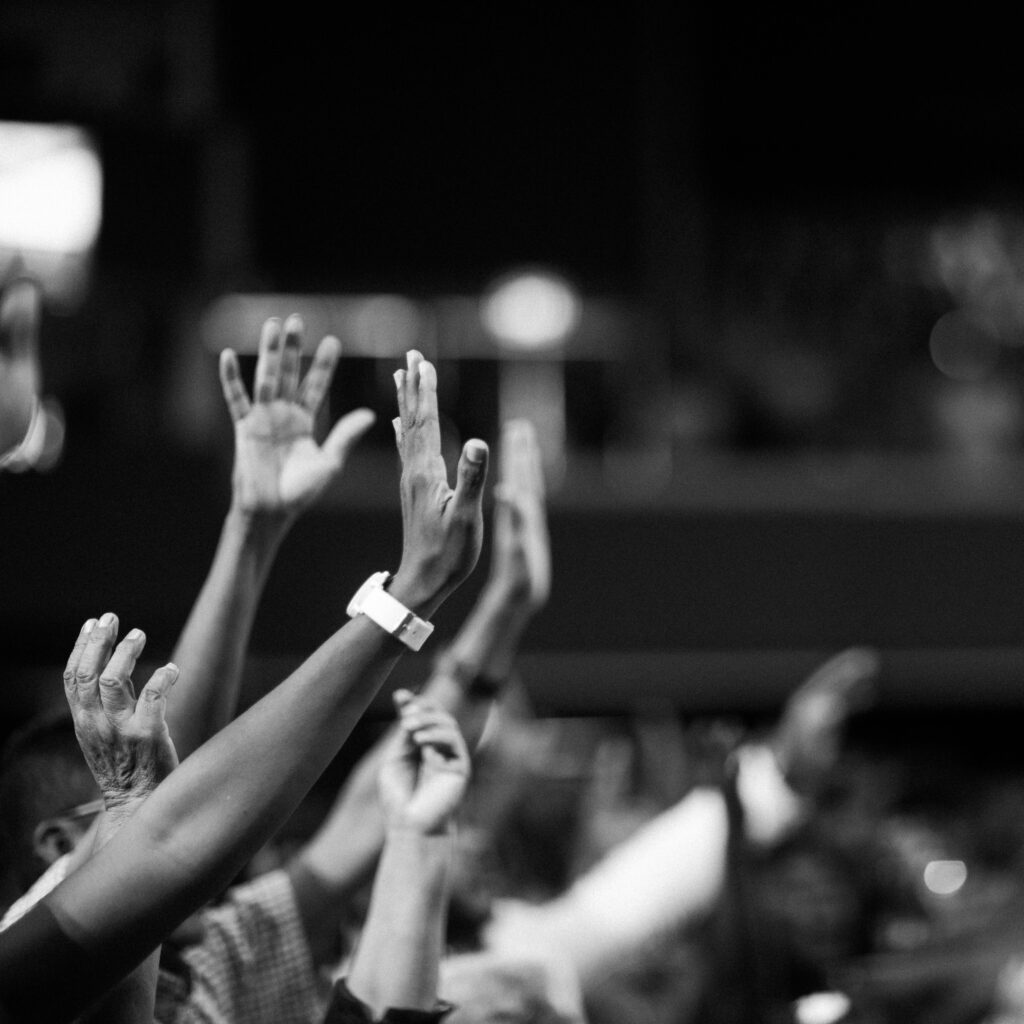 Black and white image of audience with hands raised, capturing concert energy.