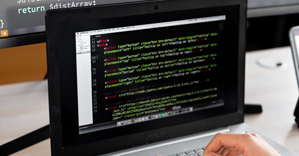 Person coding at a desk with laptop and external monitor showing programming code.